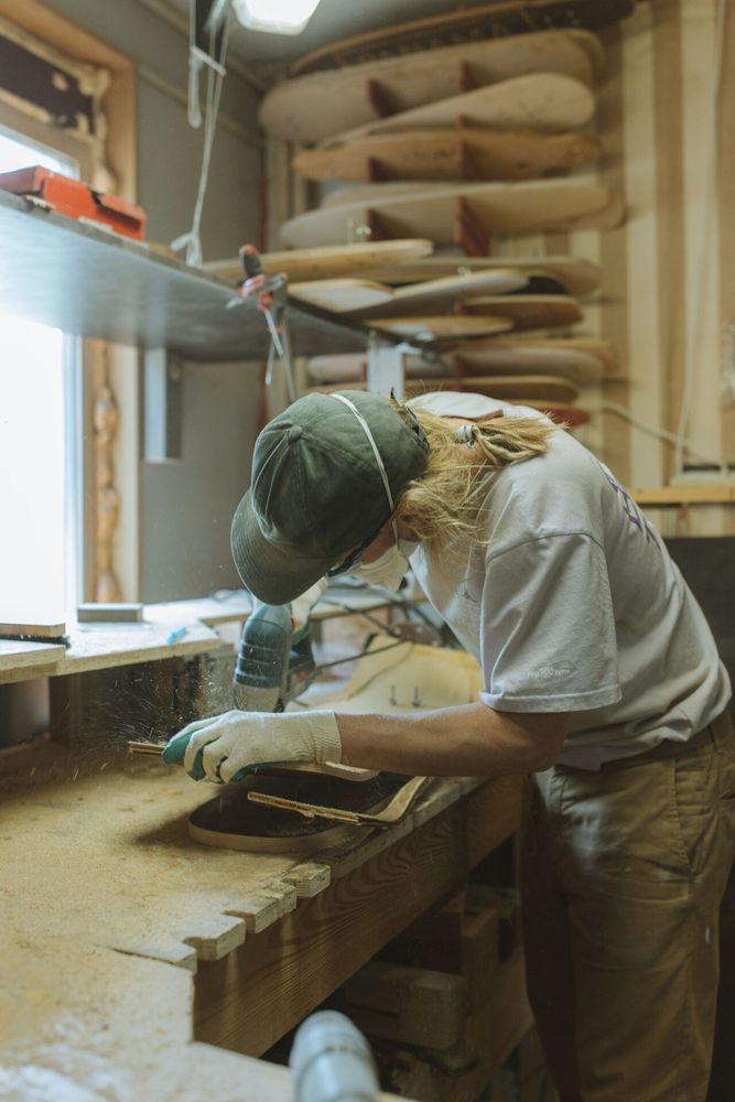 Eine Person bearbeitet konzentriert ein Werkstück in einer Holzwerkstatt